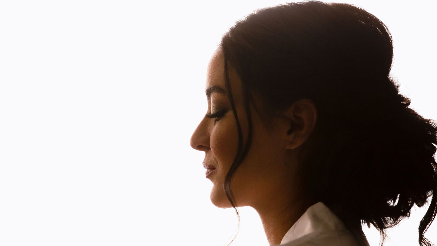 Elegant side profile silhouette of a woman with her hair up against a bright white background.