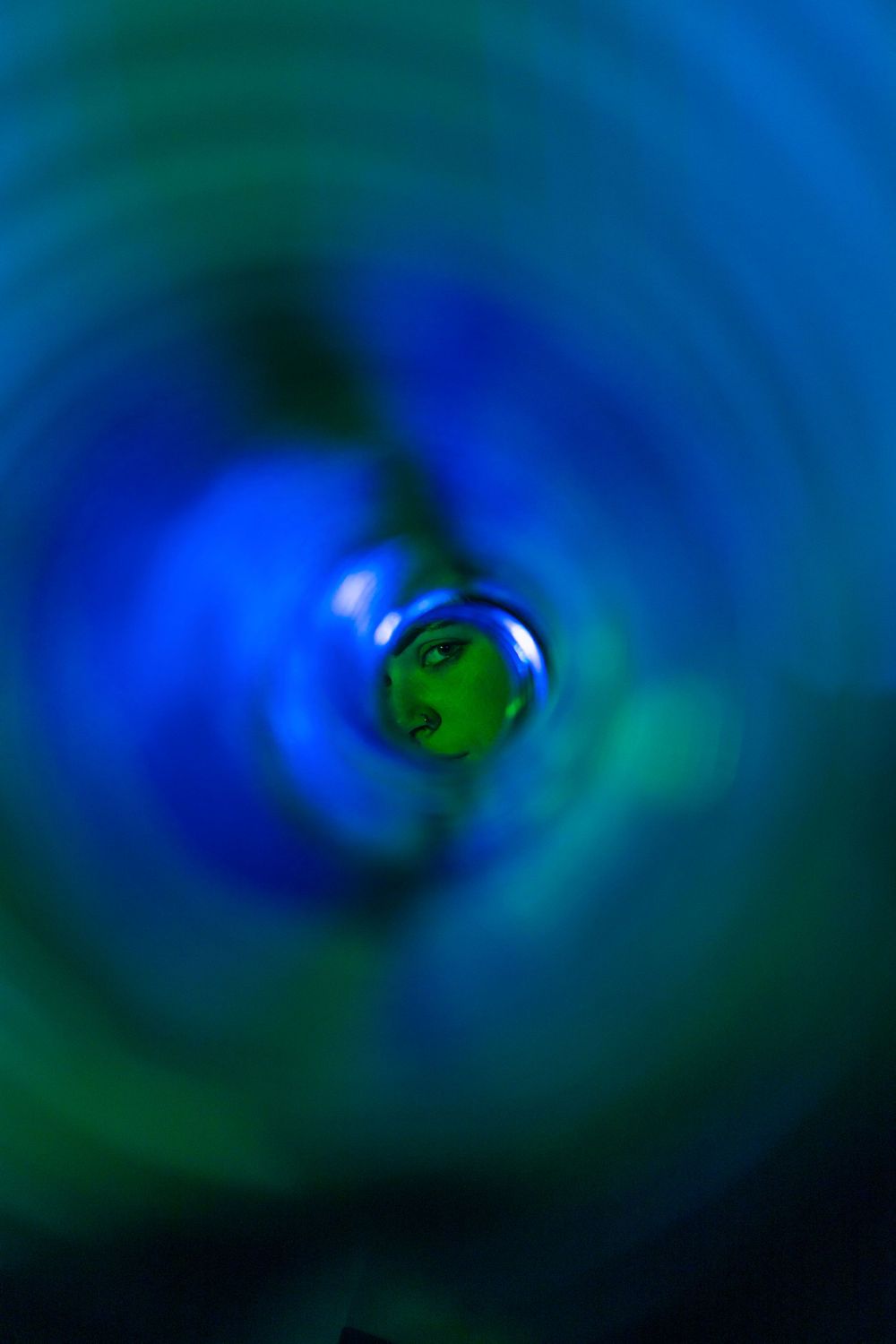 Abstract blue and green circular patterns creating a swirling effect in dark background.