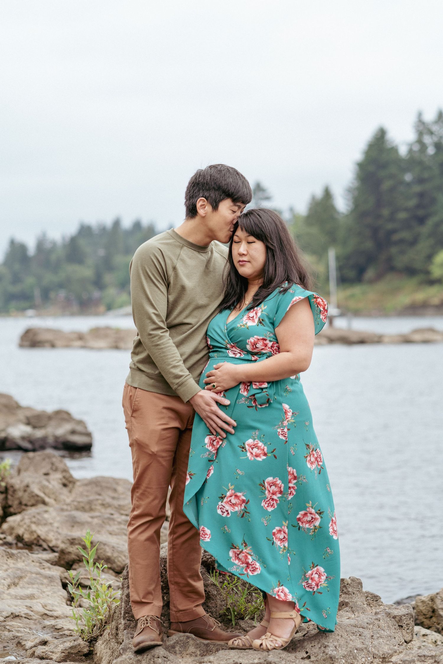 Expecting couple hugging near rocks at lake in Oregon, natural maternity session in the Pacific Northwest.
