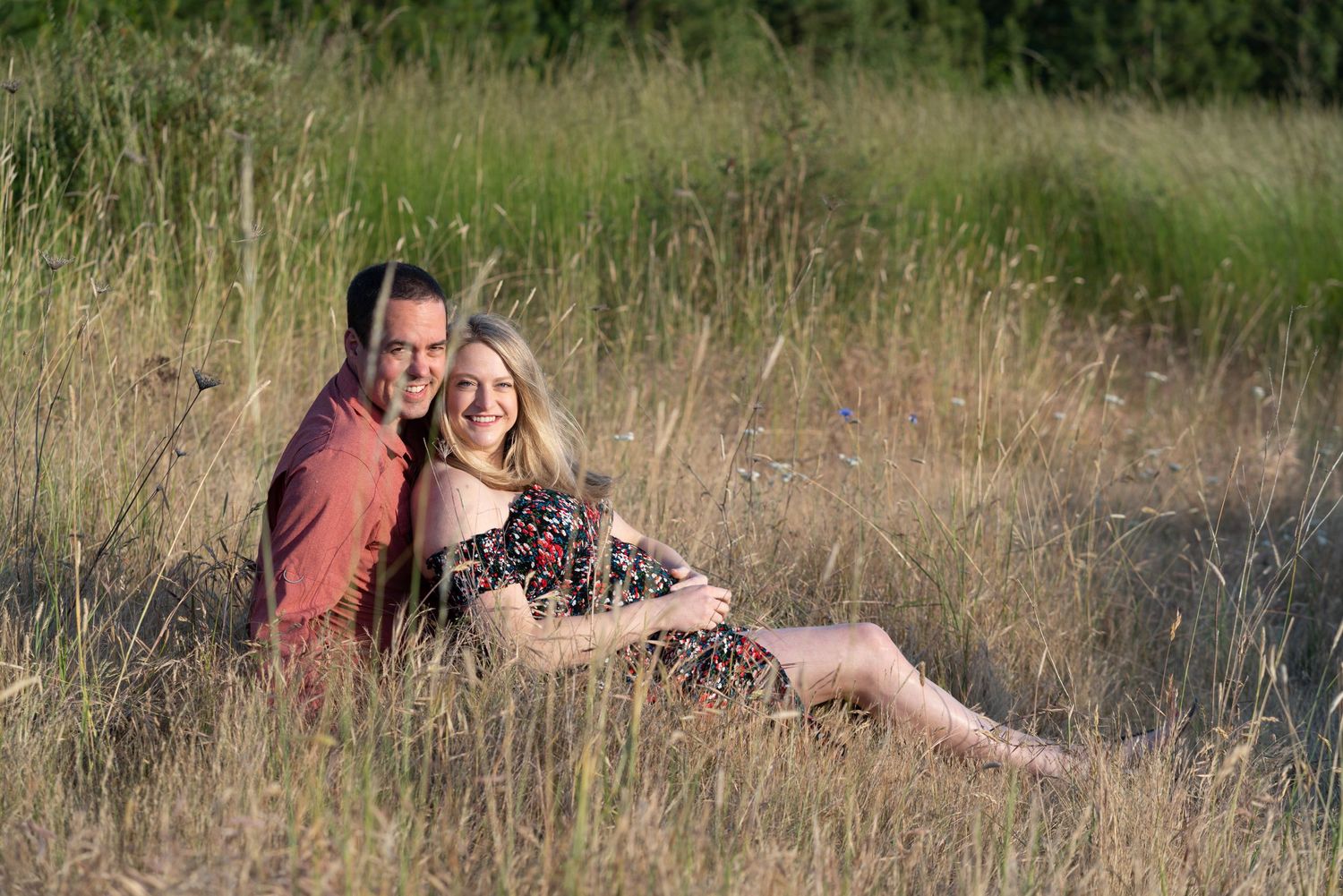 Outdoor maternity session in Washington State, couple relaxing in meadow with fall light and soft colors.
