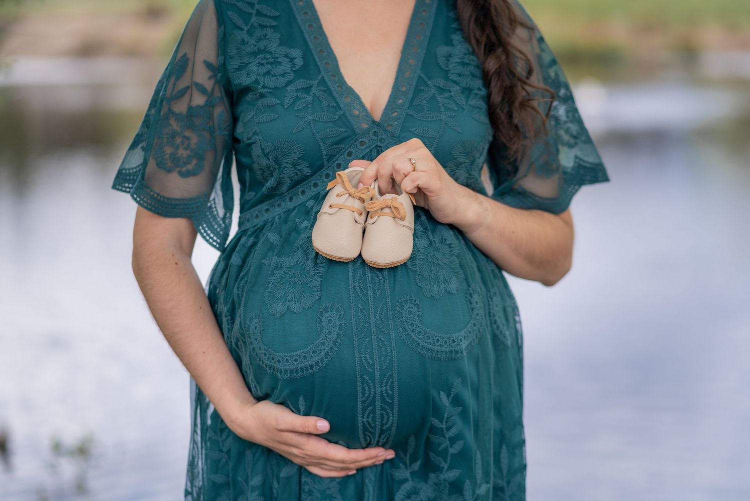 Soft and elegant close-up of mother holding baby shoes on her belly, Washington State maternity photo.