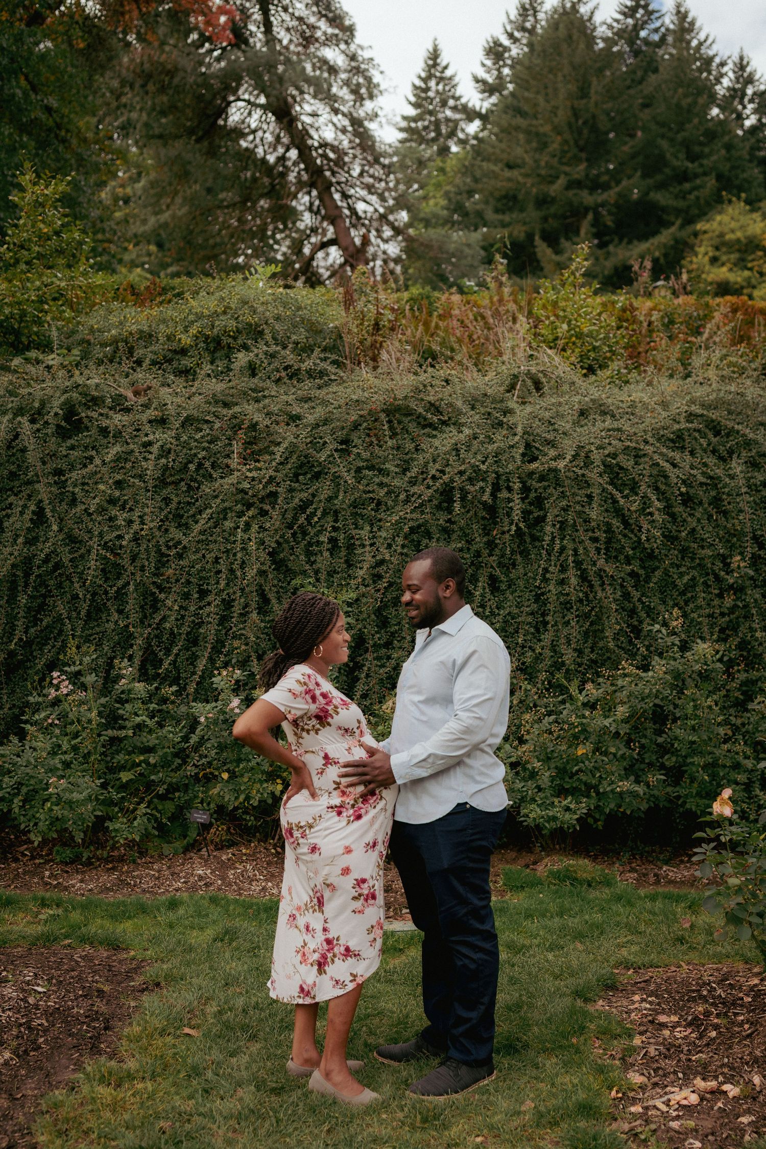 Romantic maternity moment in grassy park, expecting couple dancing in soft fall light, Portland Oregon.