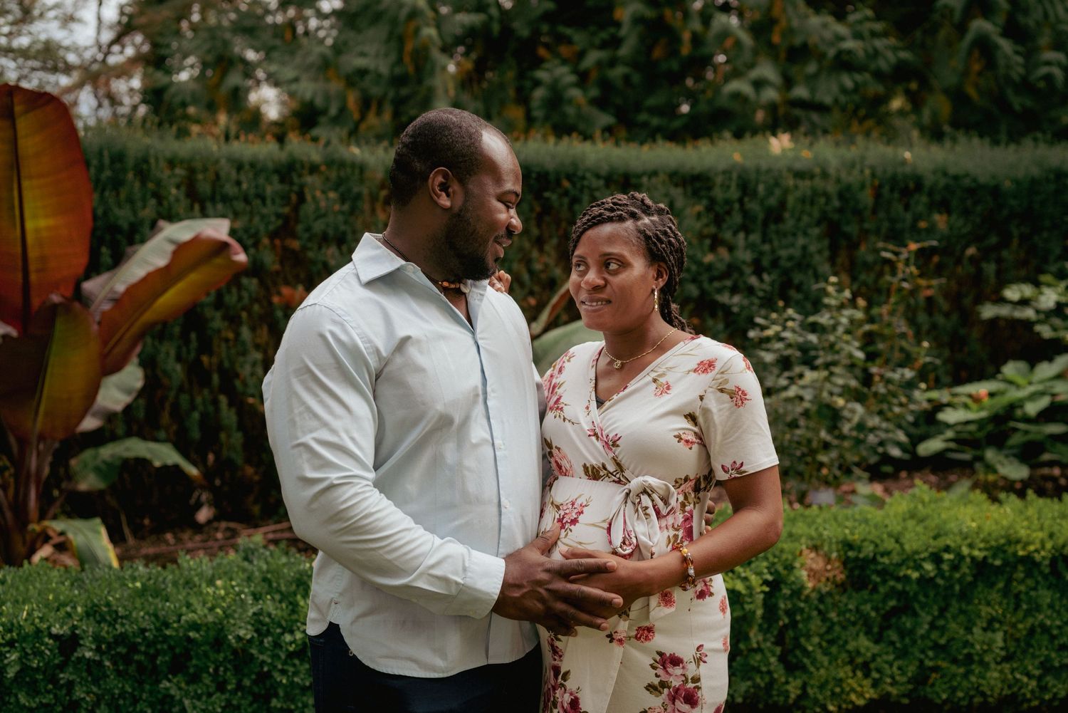 Expecting parents in floral outfits holding belly, intimate garden maternity session in the PNW.