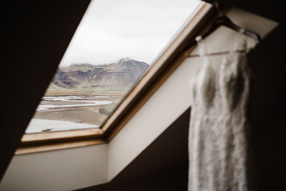 Wedding dress hanging by a skylight window with mountain views in the background.