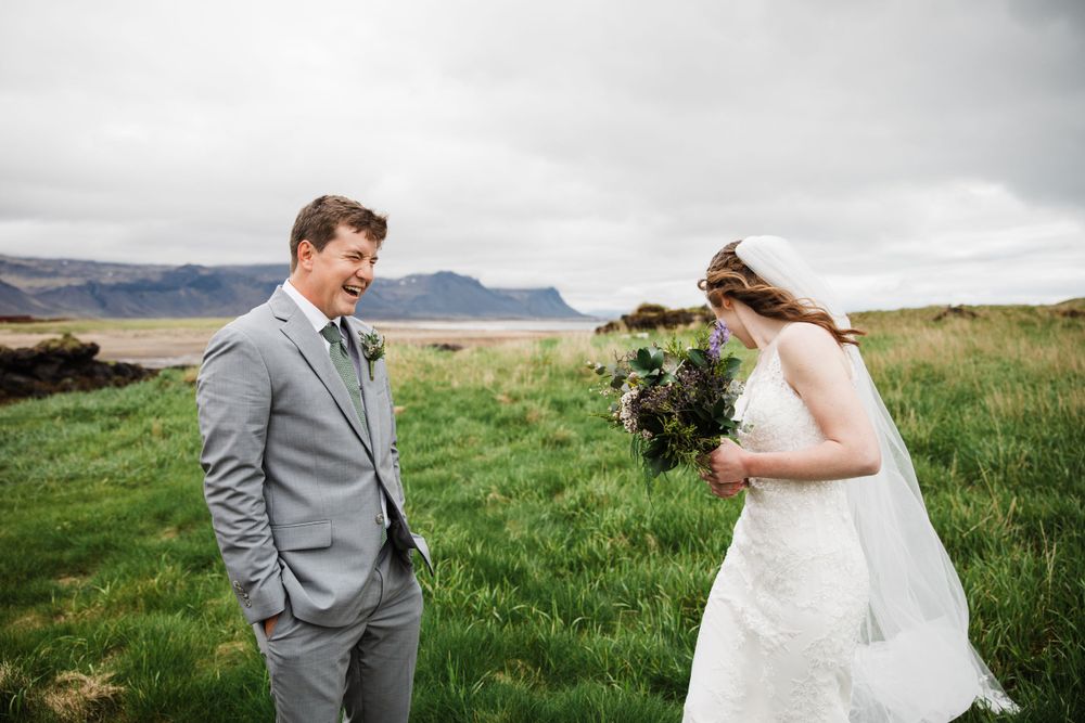 Couple shares wedding moment in windswept field with mountain vista.