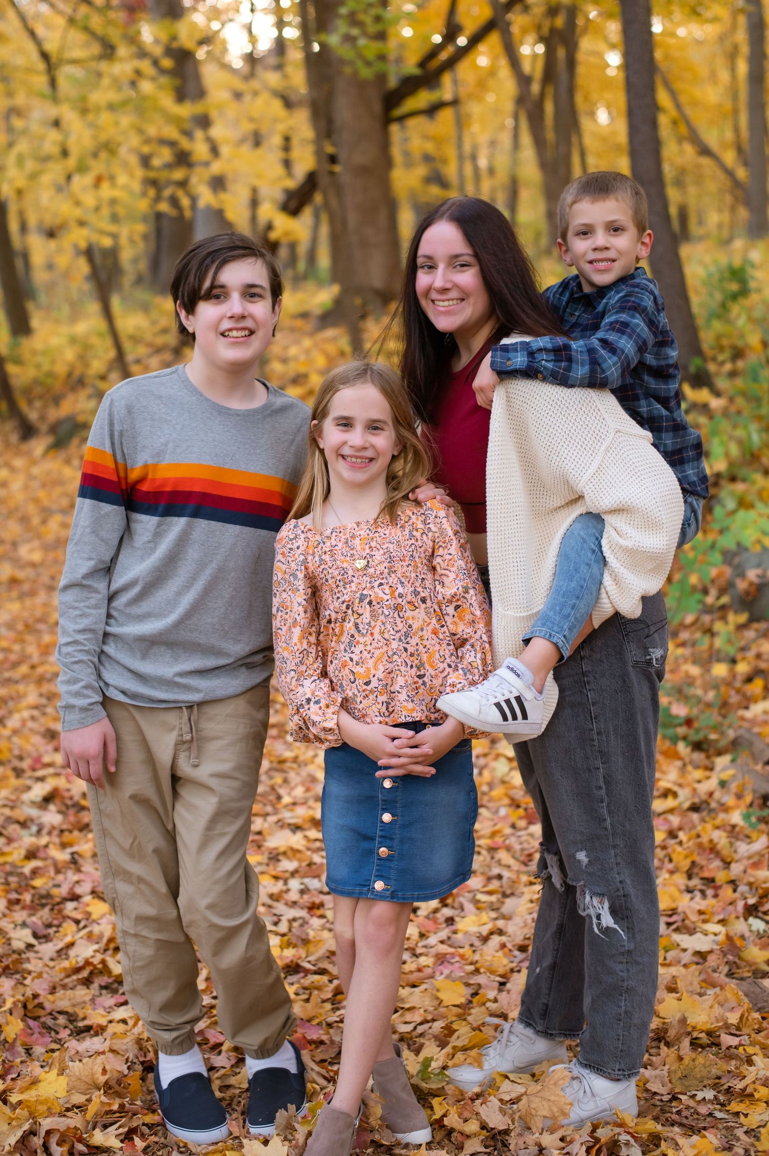 Group poses together among fallen autumn leaves with golden trees in background.