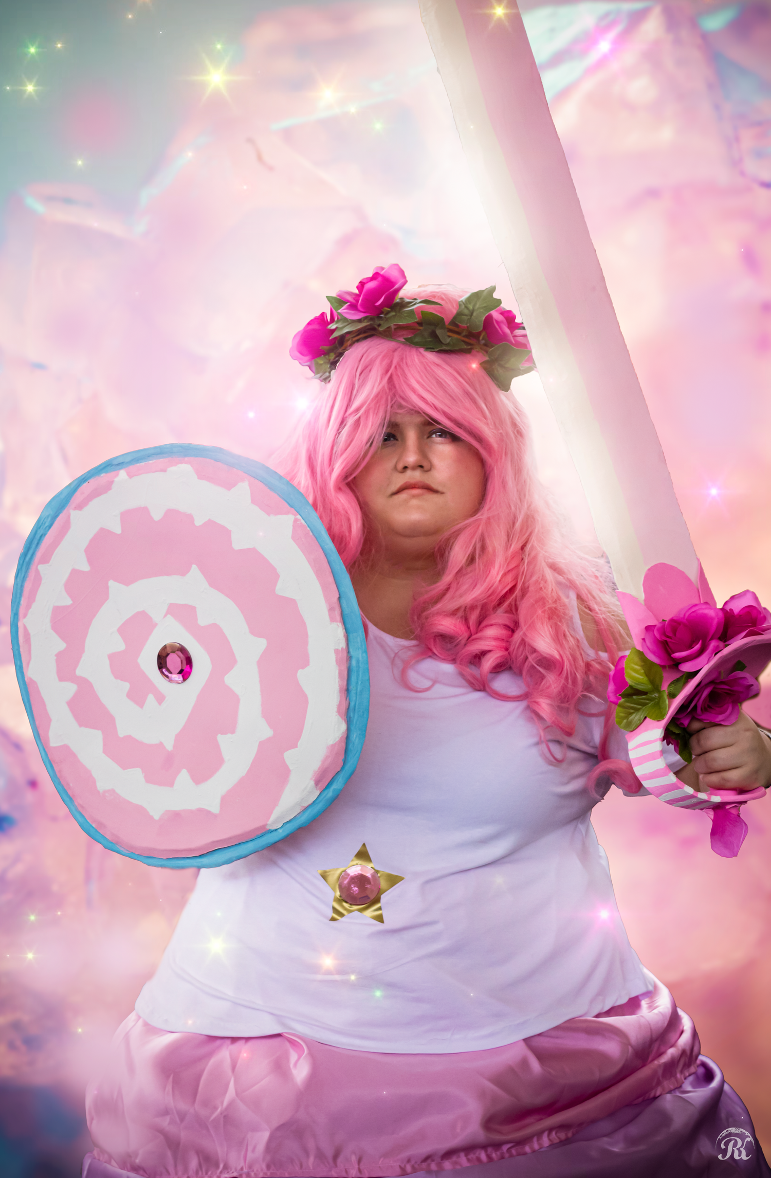 Fantasy-themed cosplay featuring pink wig, flower crown and circular shield with sparkly background.