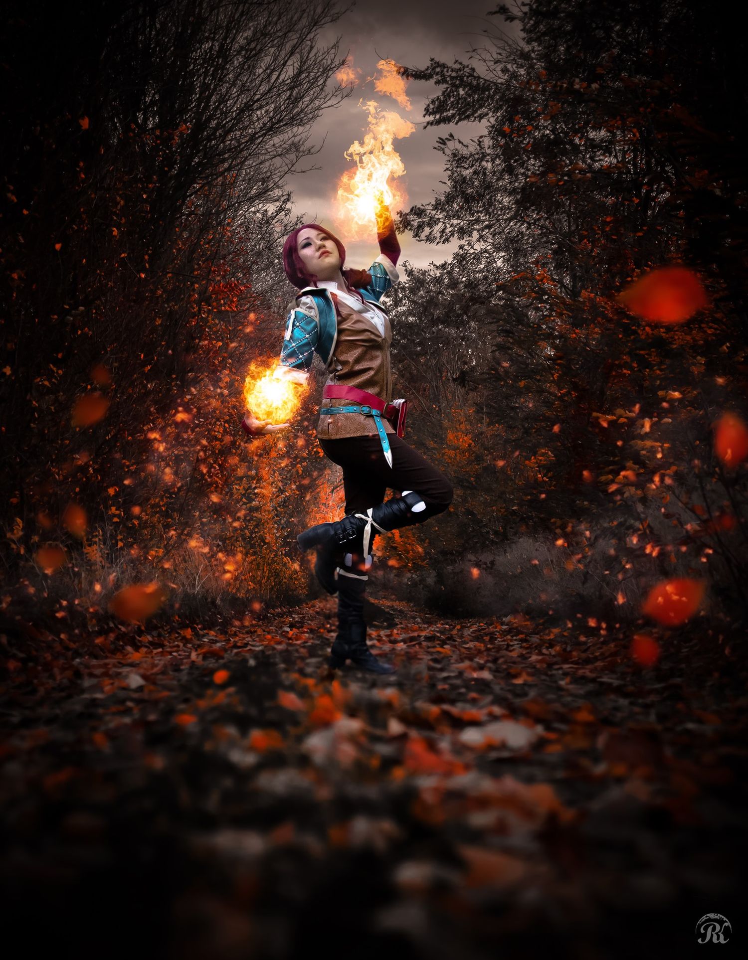 Magical scene of figure wielding fire spheres in autumn forest with glowing orange particles.