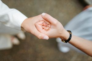 Close-up of hands holding delicate wedding rings in palm.