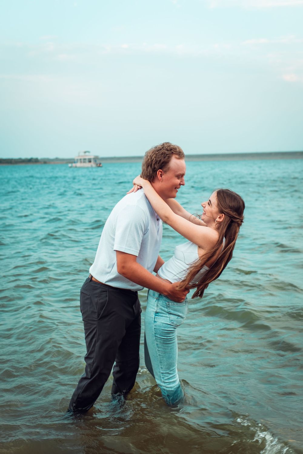Playful couple splashing and embracing in turquoise ocean waters.