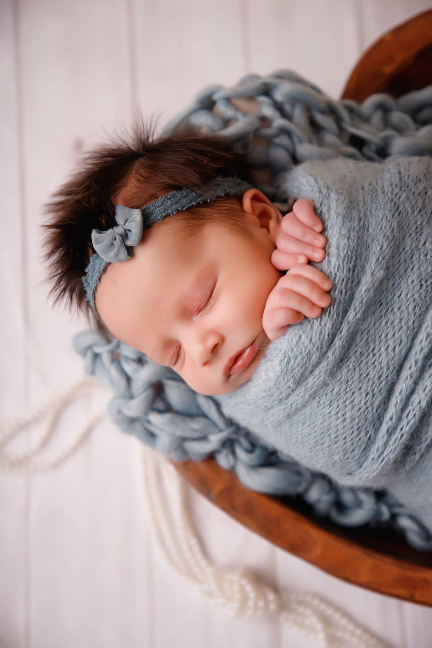 Sleeping newborn wrapped in soft gray blanket with matching headband.