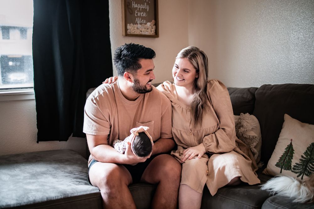 A couple in neutral-colored clothing shares a tender moment on their living room couch.