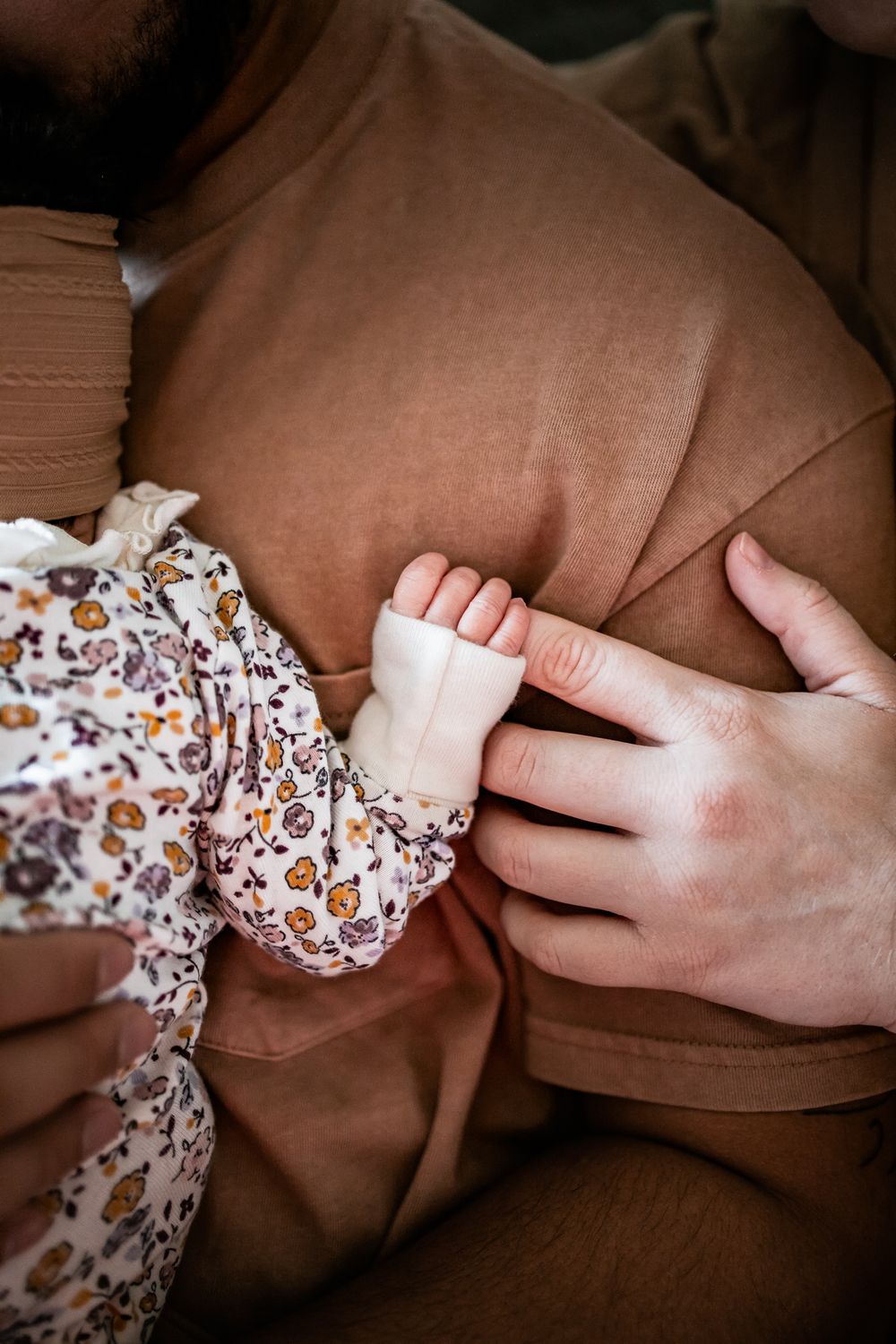 Close-up of tiny baby feet being held by gentle hands against beige fabric.