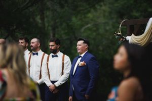 Groomsmen stand together at outdoor wedding ceremony with groom Watching Bride walk down the aisle. Ceremony in Northern Wisconsin