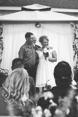 Black and white photo of a wedding ceremony under a decorated white tent gazebo with gathered guests. Wisconsin Weddings