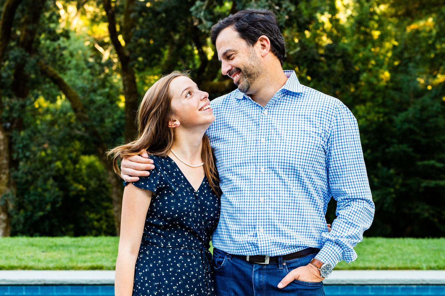 Romantic couple poses together outdoors during golden hour in a garden setting.