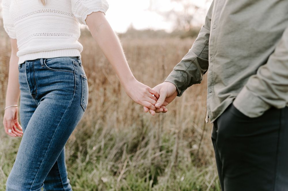Casual couple strolling through meadow wearing jeans and neutral colors.