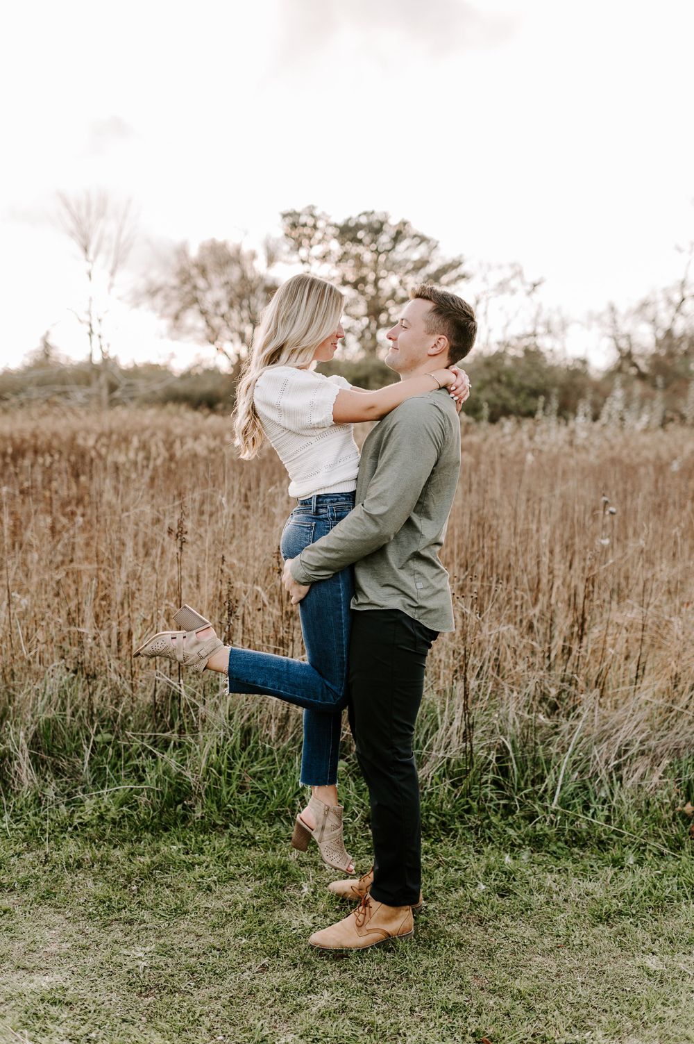 Couple dancing and spinning together in natural meadow setting.