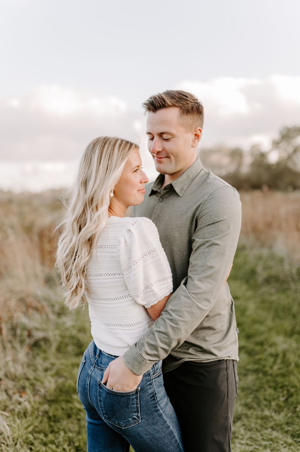 Couple sharing tender moment in casual attire against natural backdrop.