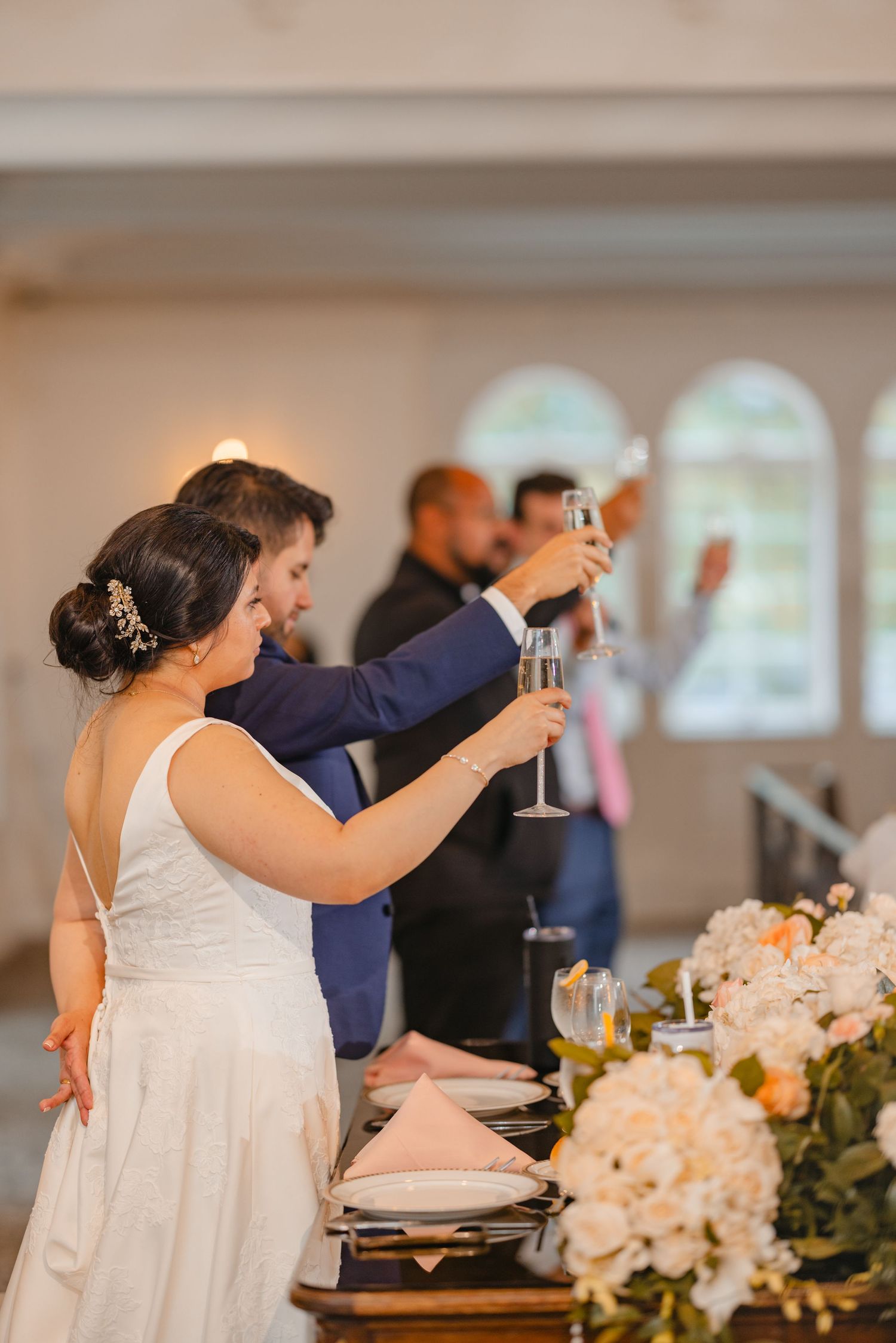 Bride and groom raising champagne glasses in a toast at their elegant wedding reception.