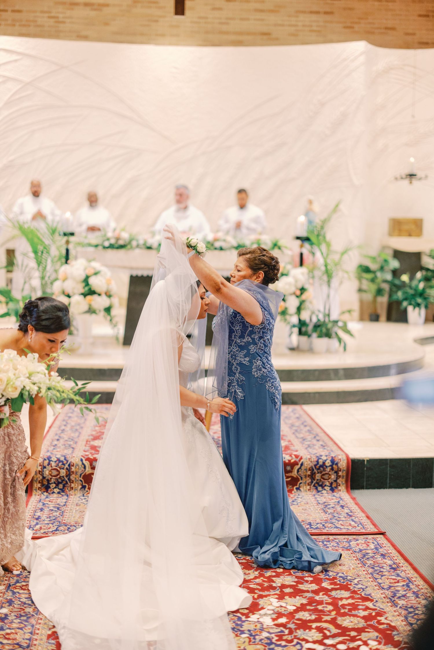 Mother of the bride adjusting the veil over the bride during a church wedding ceremony.