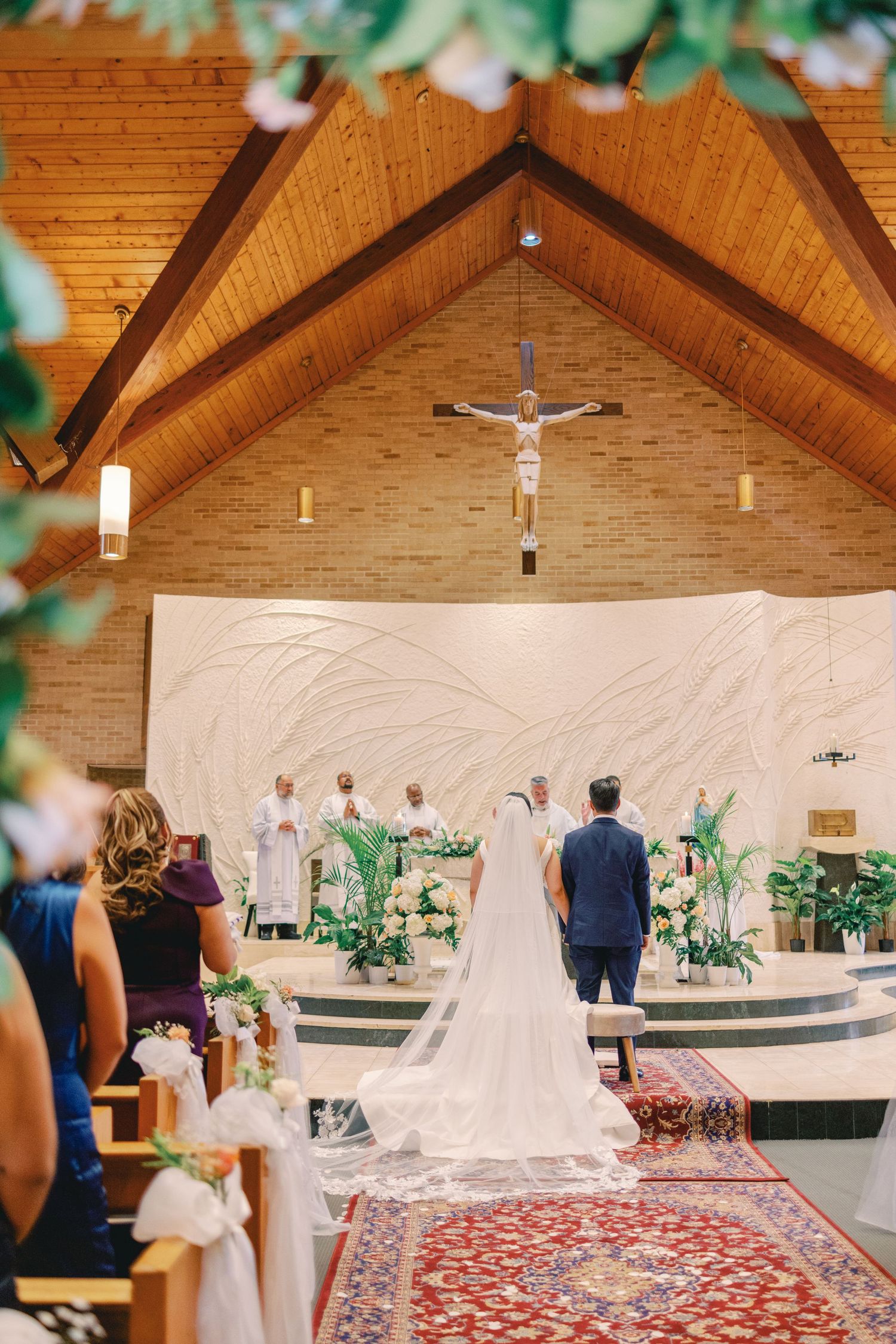 Bride and groom stand at the altar of a wooden cathedral church during their Catholic wedding ceremony.