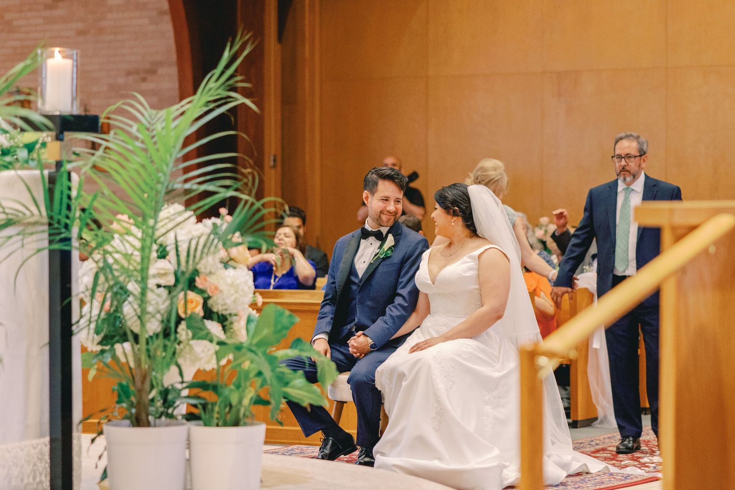 Bride and groom share a joyful moment seated at the altar during their church wedding ceremony.