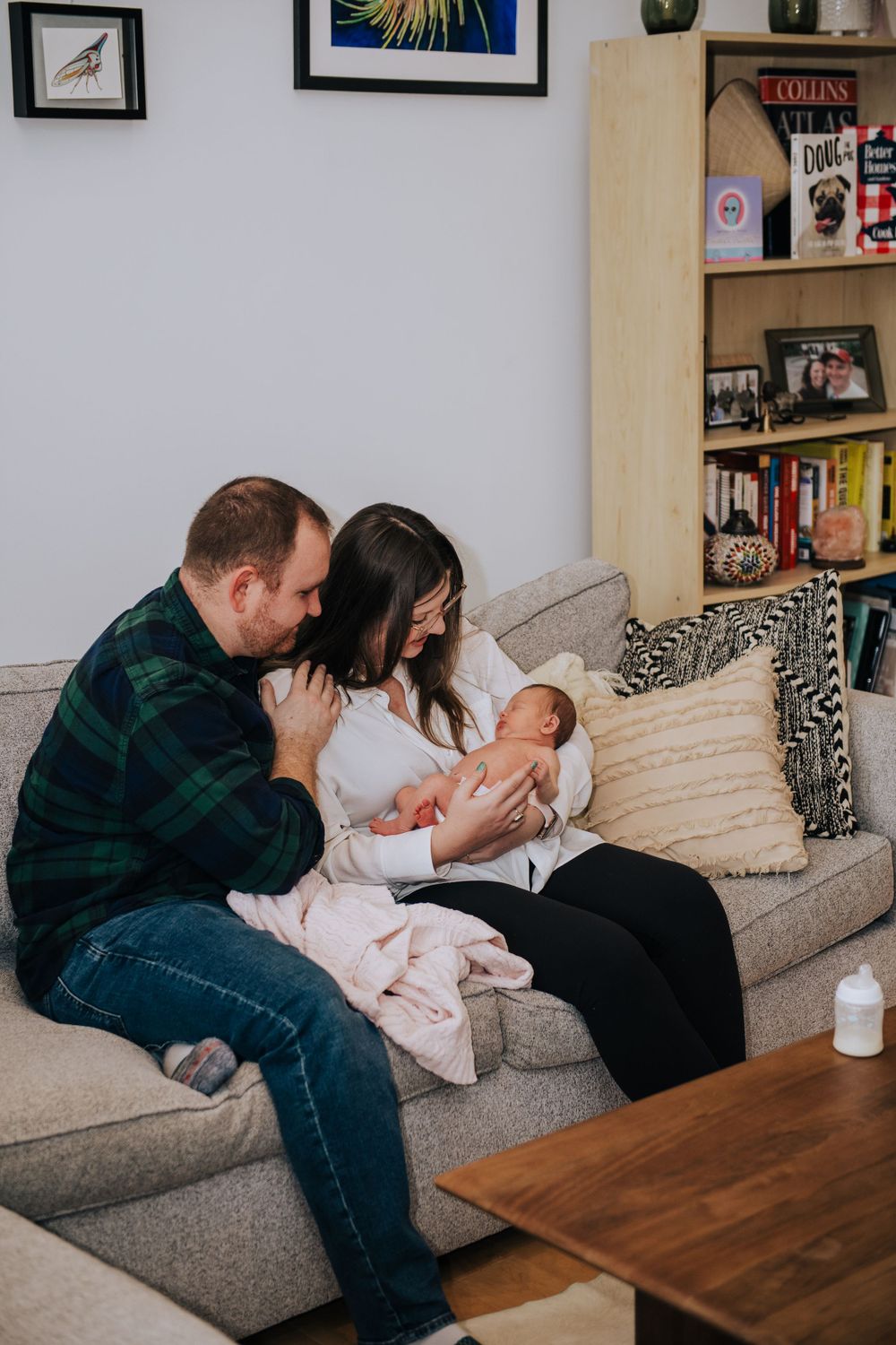 Family spending time together on grey couch with framed art on walls.