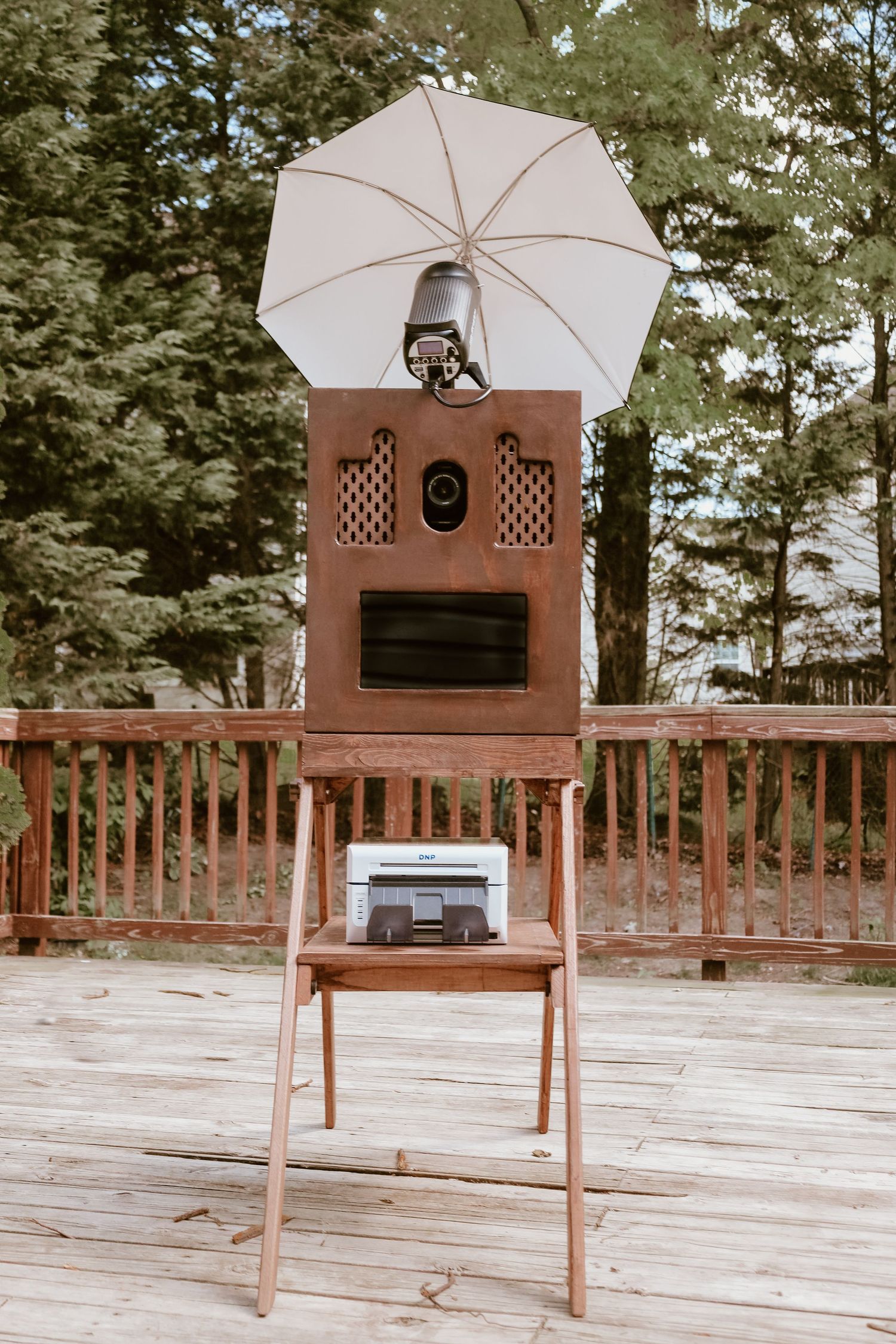 Vintage-style open-air photo booth setup with white umbrella and wooden frame at an outdoor event in the DC, Maryland, and Virginia area.
