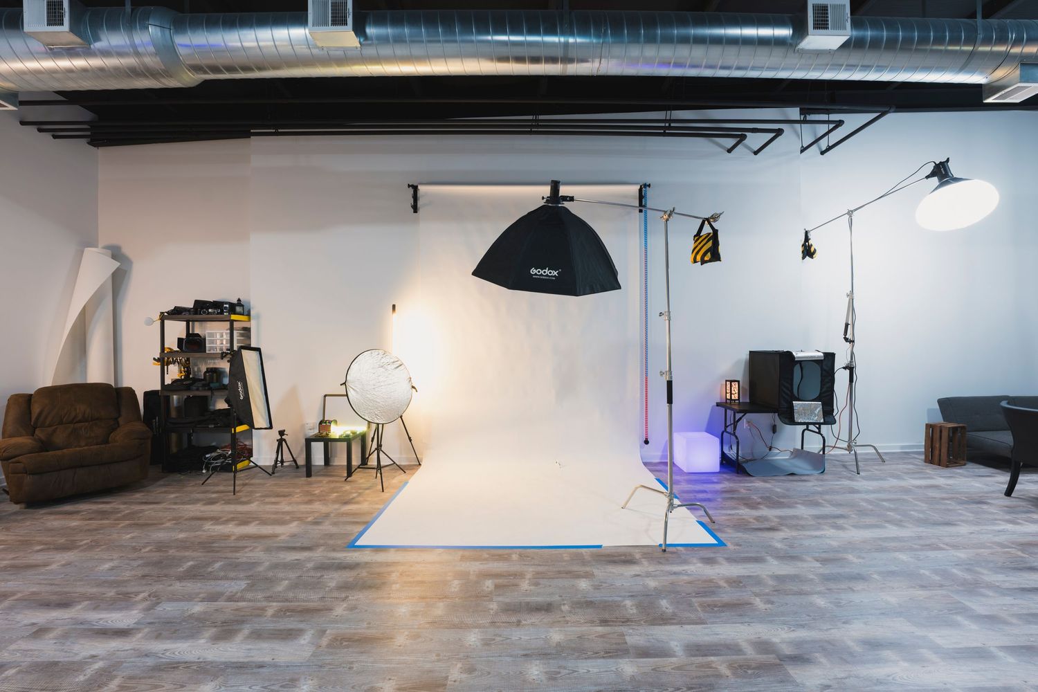Photography studio with vintage furniture, white backdrop, and professional lighting setup.