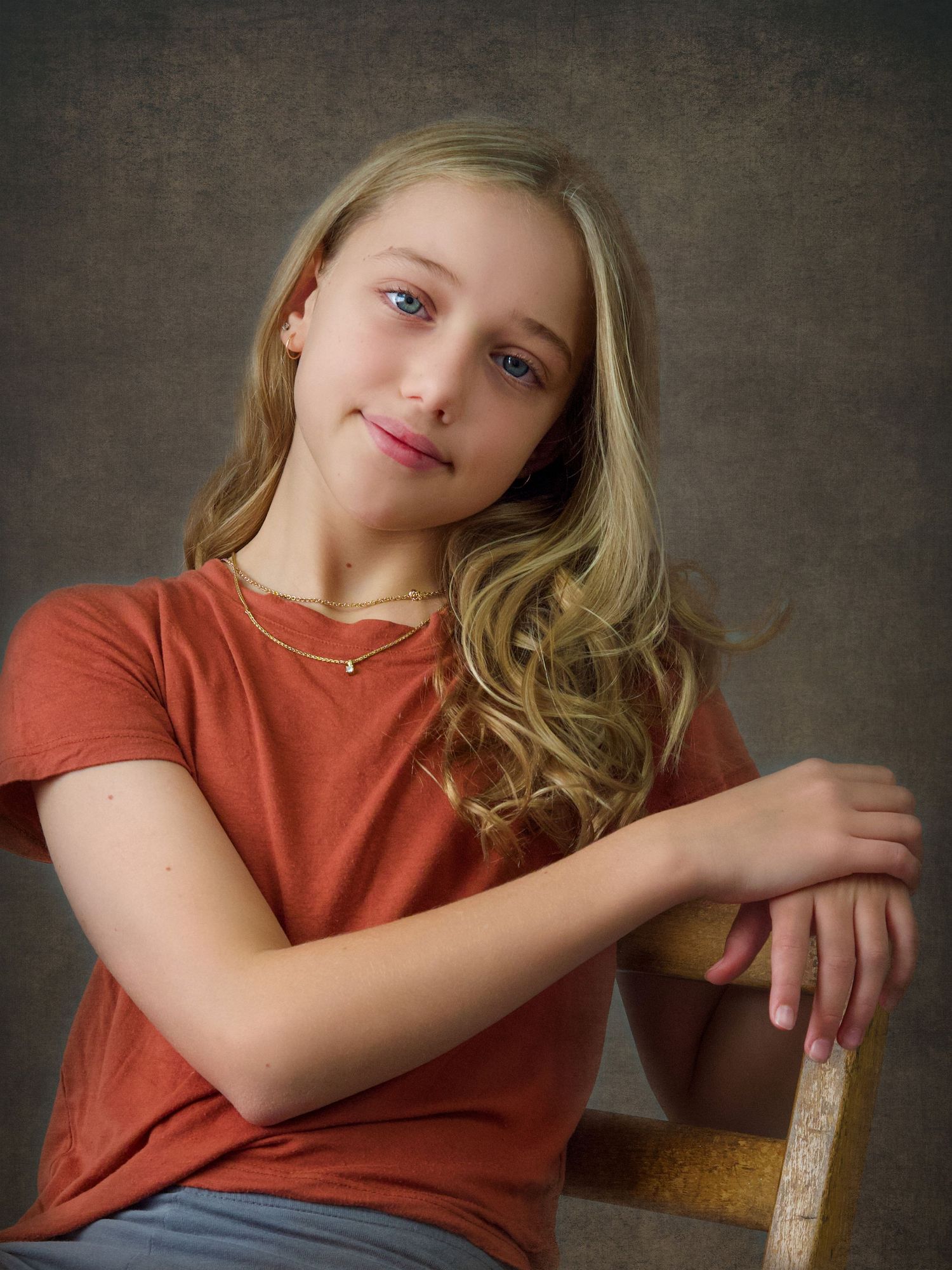 Young girl with long blonde hair, casual sitting portrait wearing an orange tshirt