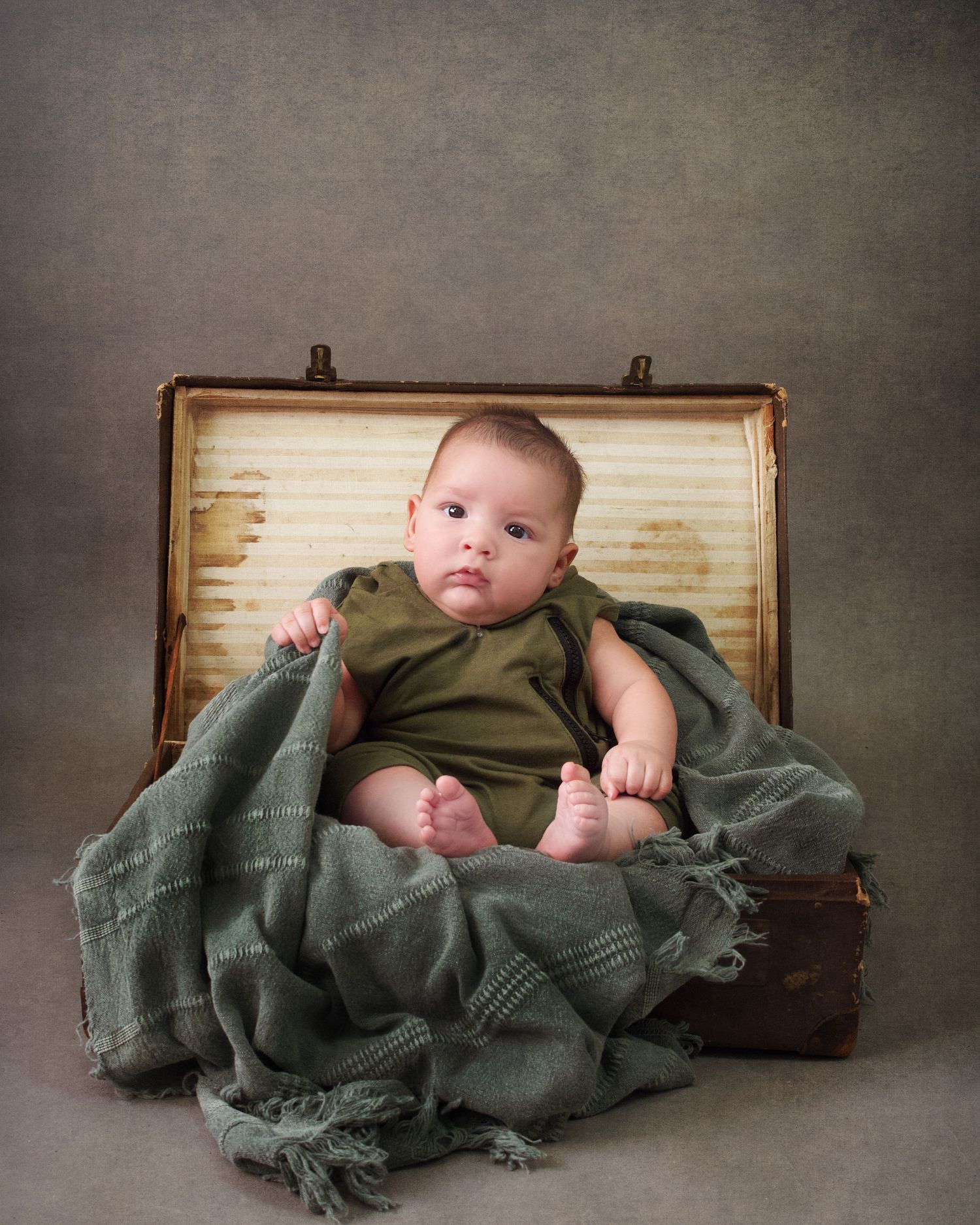 Baby boy casual portrait sitting in a suitcase wearing earthy tone colours