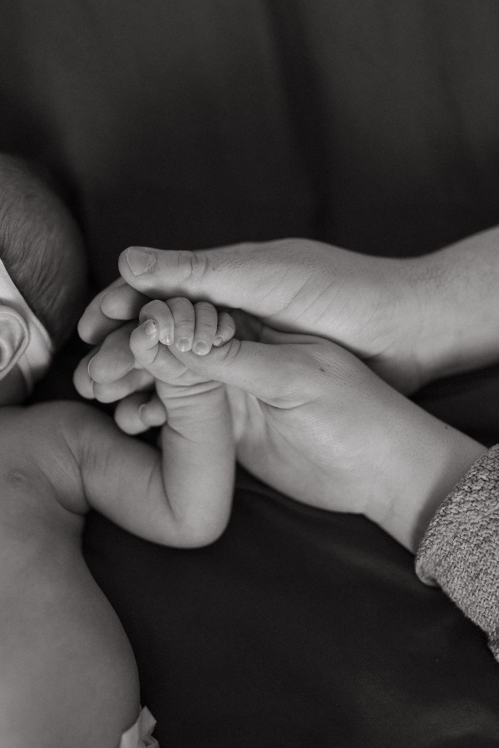Black and white close-up of parent holding newborn baby's tiny foot.