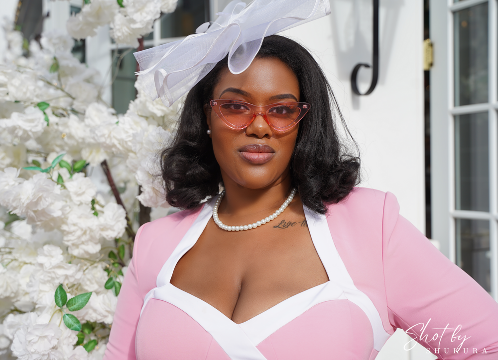 A springtime portrait featuring someone in a pink and white dress with pearls among white flowers.