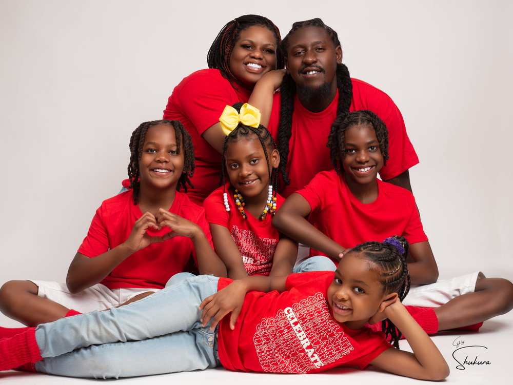 Family portrait of group wearing matching red shirts lying together on white background.