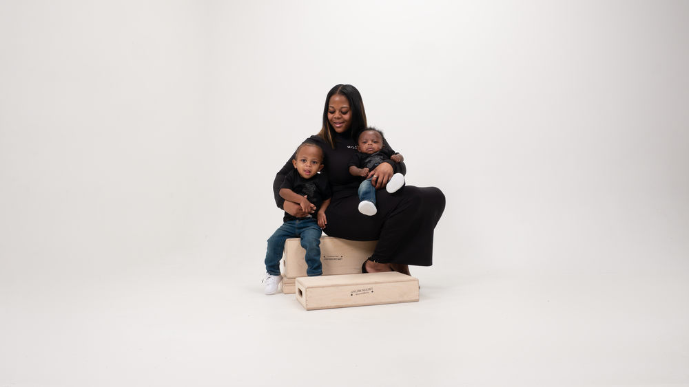 A studio portrait of a family in casual attire sitting together against a white background.