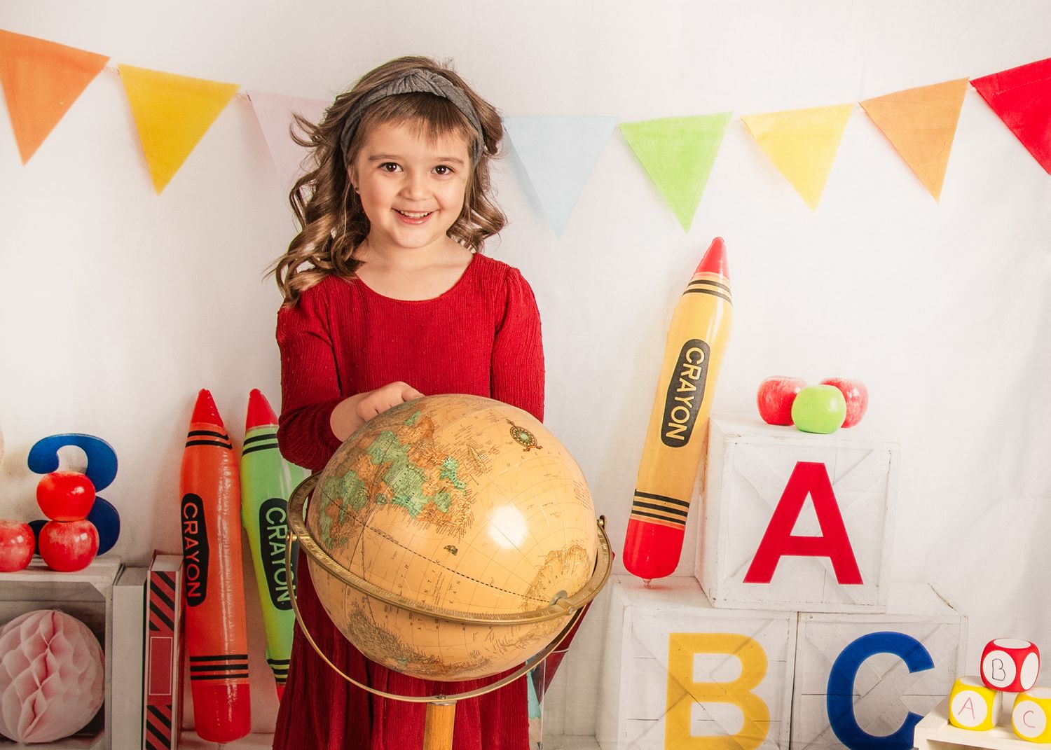 School classroom decorated with colorful alphabet letters, crayons and bunting with student holding vintage world globe.