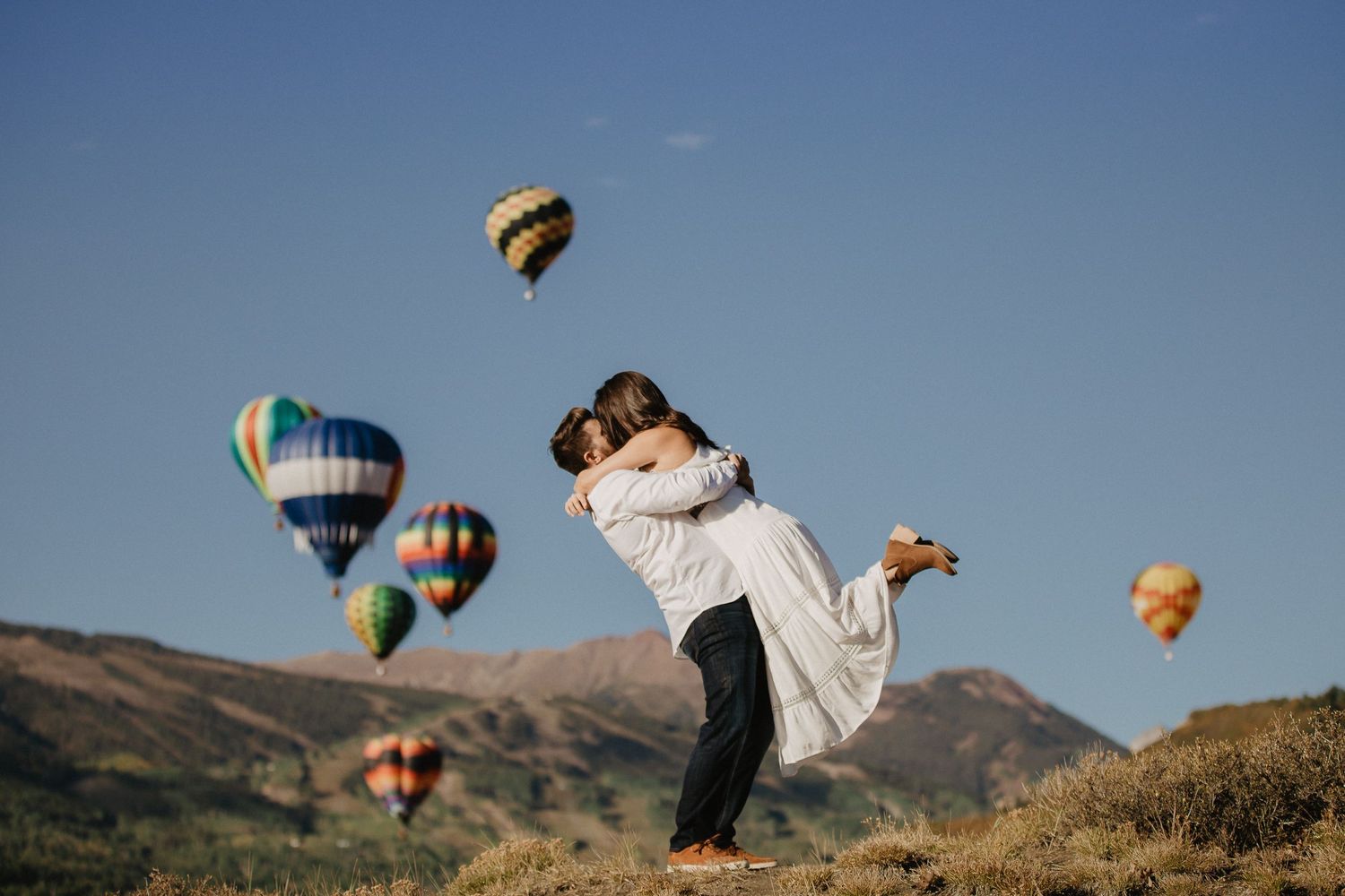 Couple embracing with hot air balloons in the background