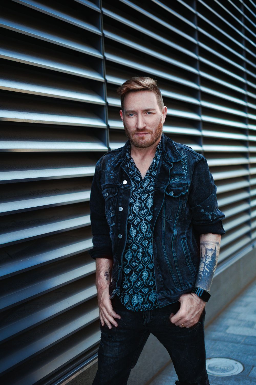 Urban portrait against modern metal slat wall with dramatic lighting.