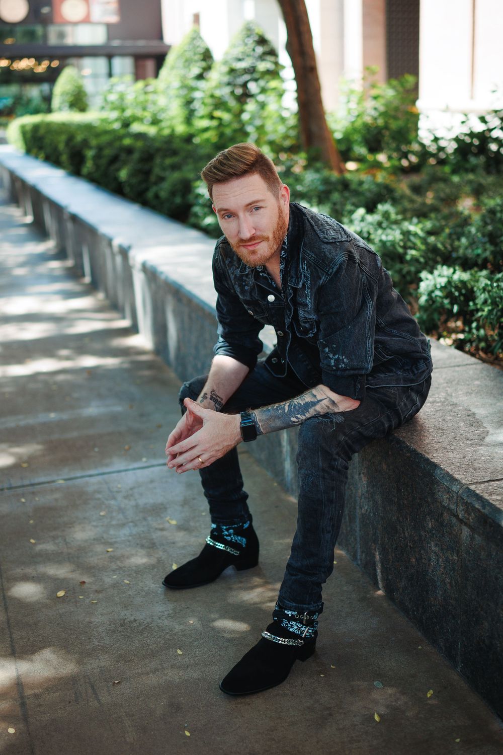 Casual outdoor portrait session with denim jacket against concrete wall.