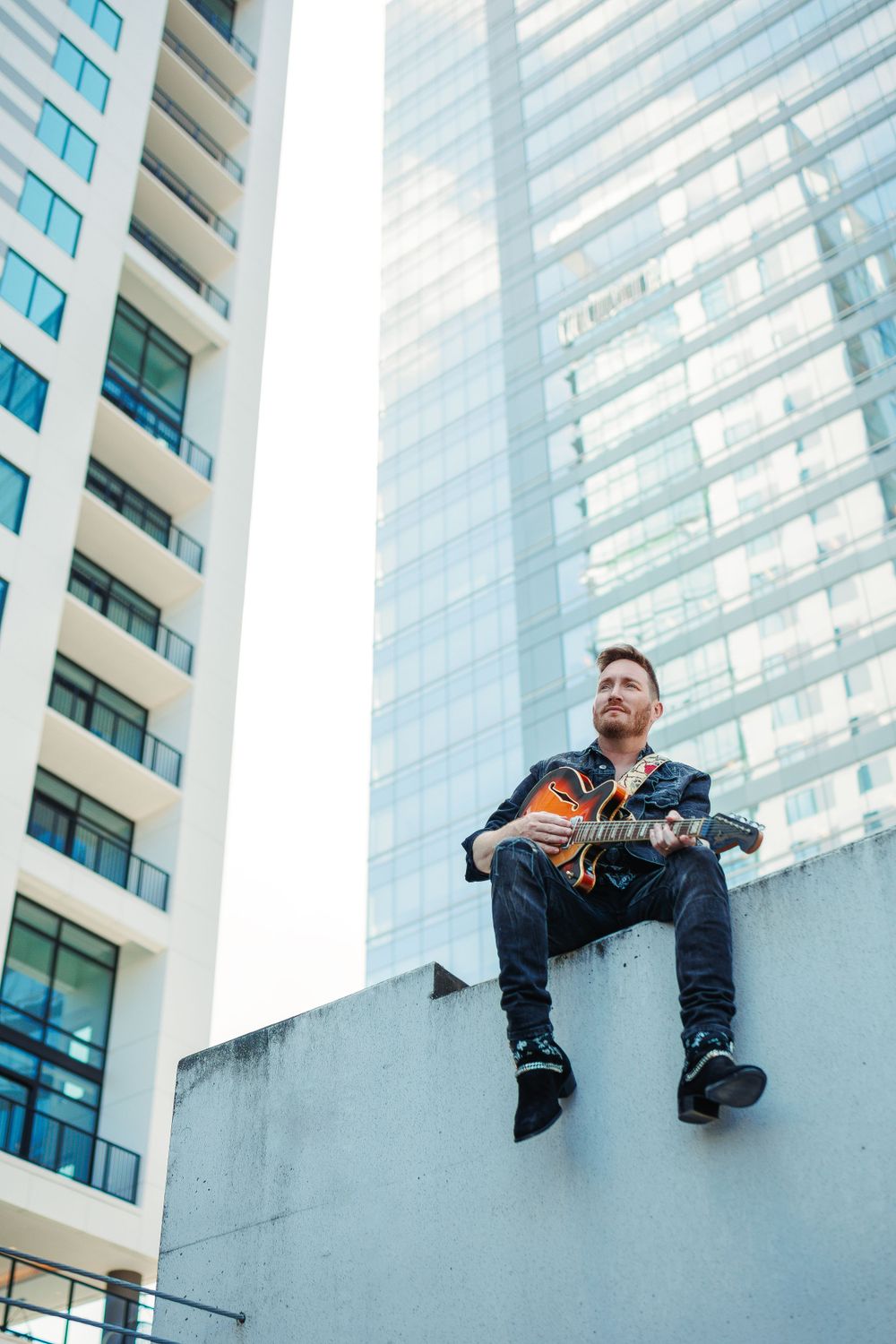 Creative rooftop pose against modern glass high-rise building.