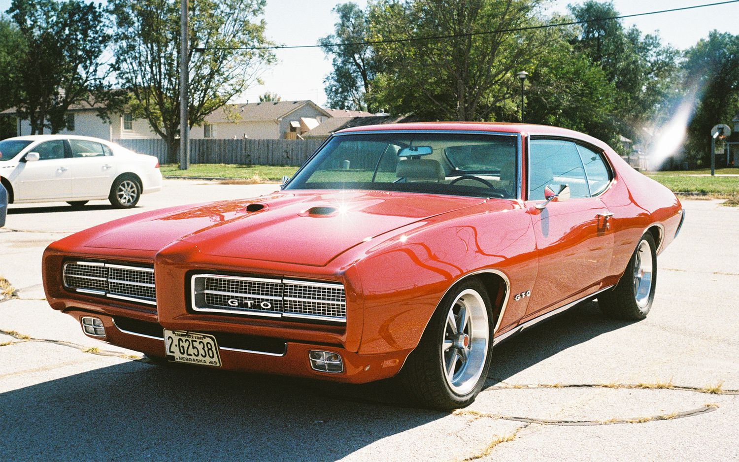 Classic orange Pontiac GTO muscle car parked on residential street.