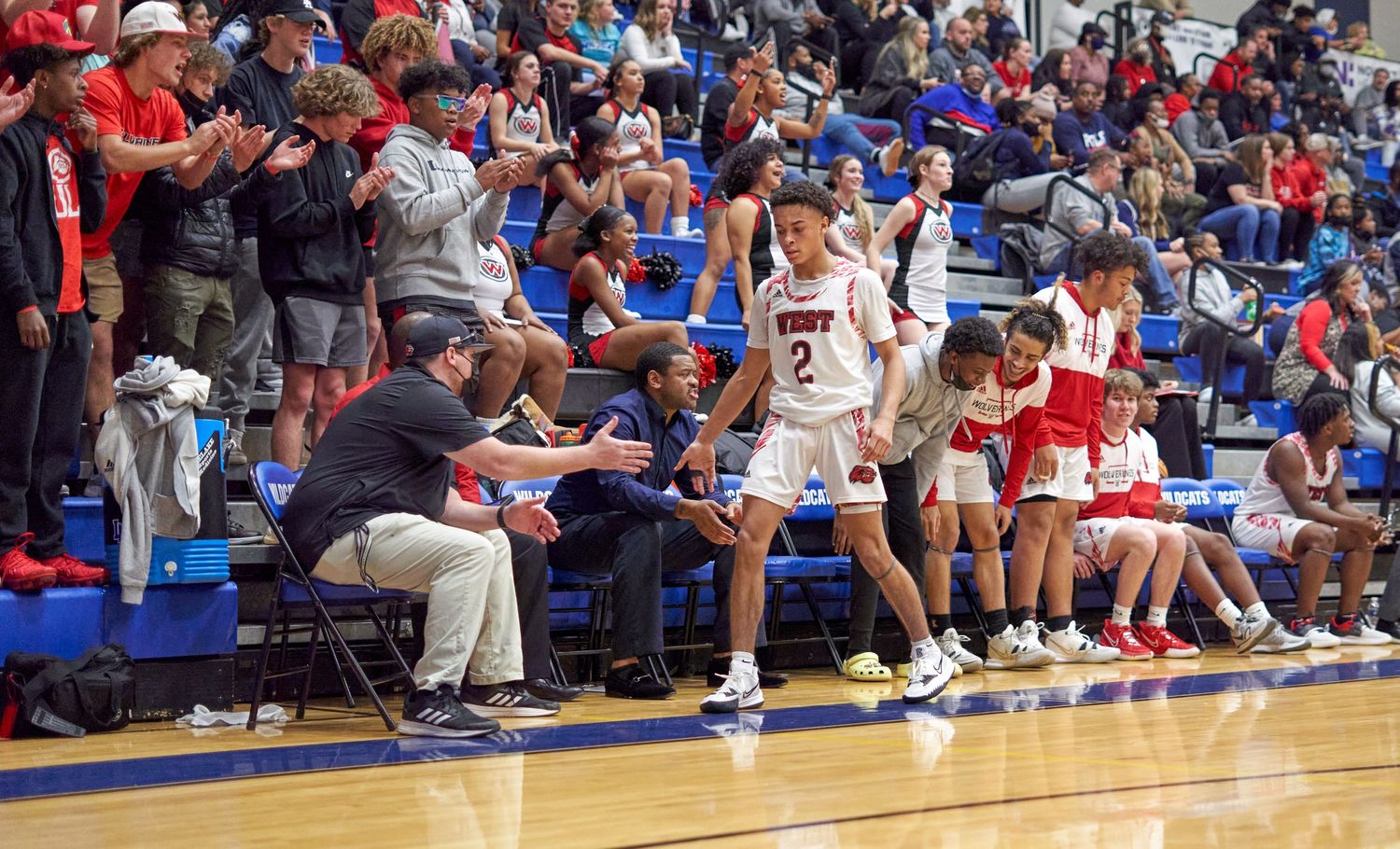 Basketball players and coaches on sideline during intense game moment.