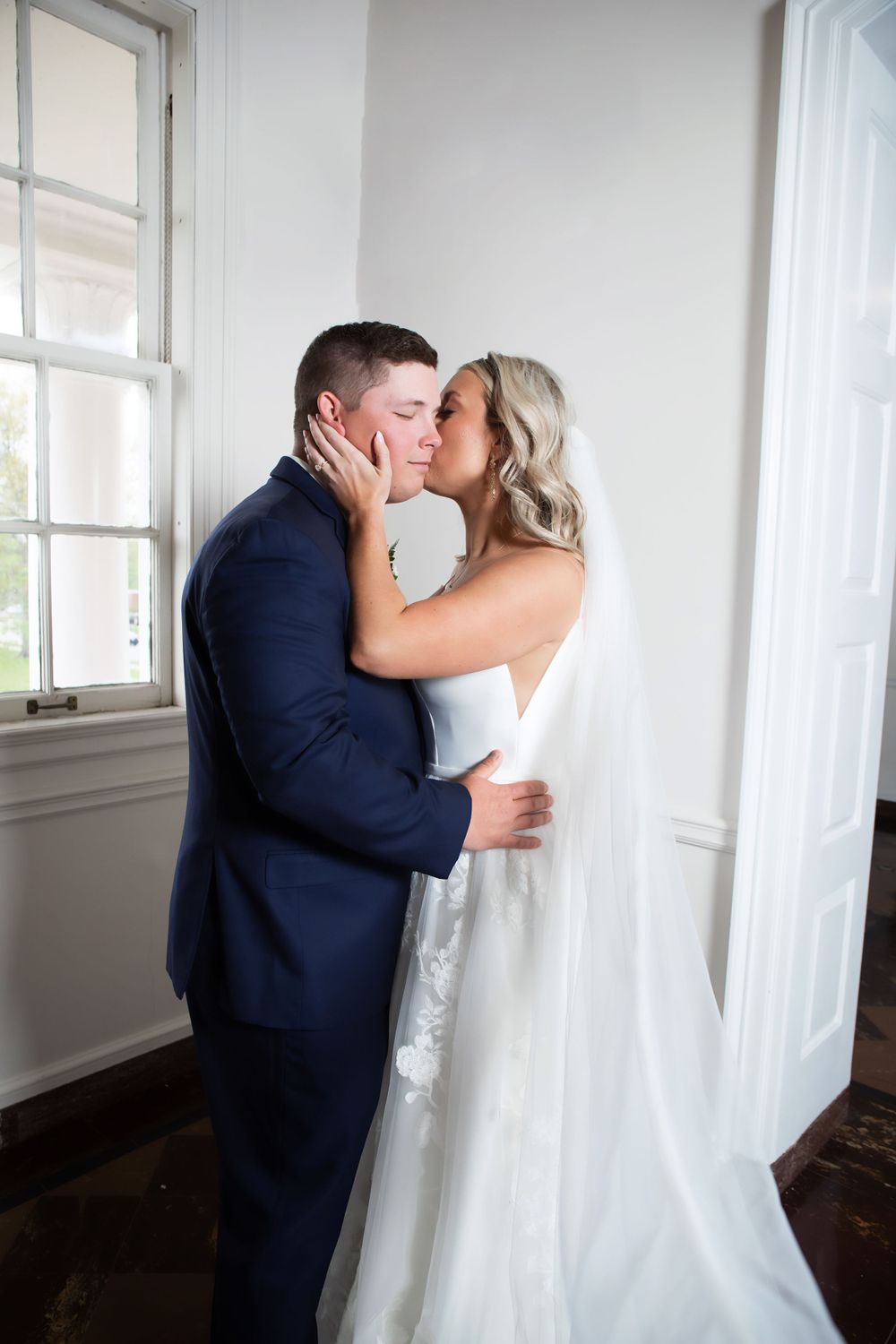 Romantic embrace by window in elegant white church setting.