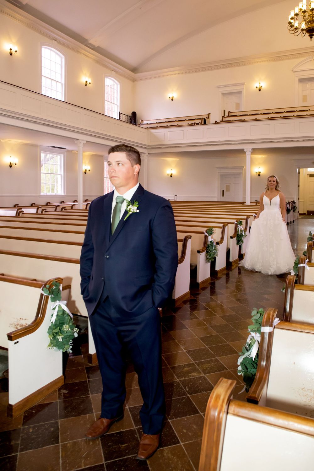Wedding ceremony venue with traditional wooden pews and elegant white interior.