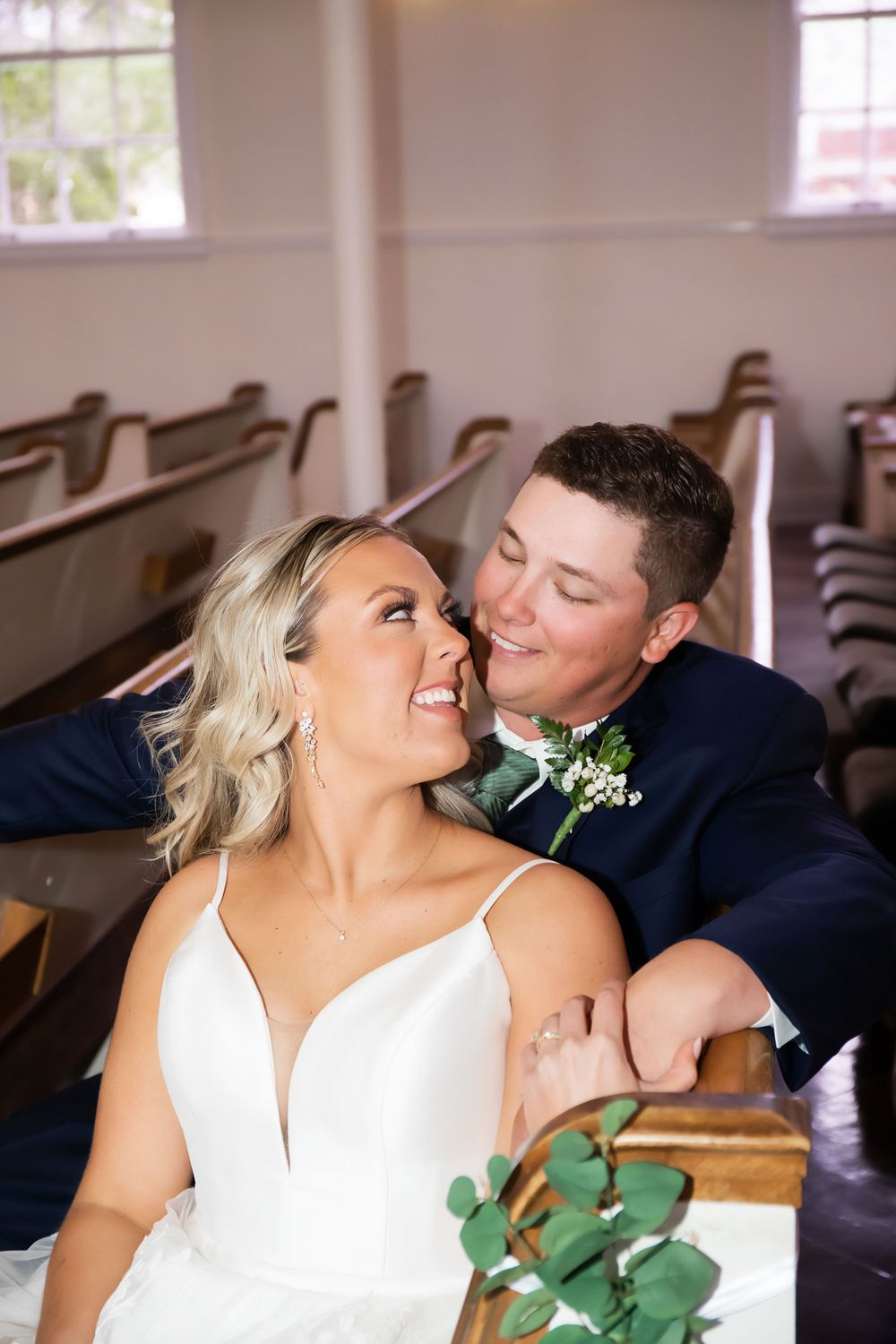 Intimate moment shared between newlyweds in church pew setting.