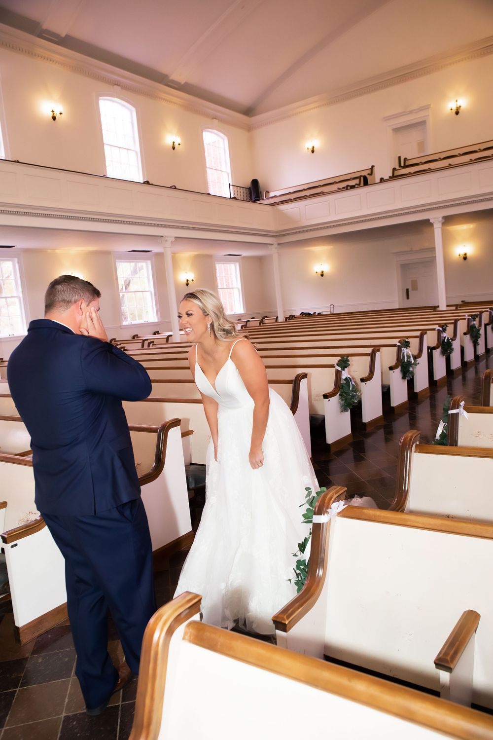 Sweet moment between couple in church pews during wedding celebration.