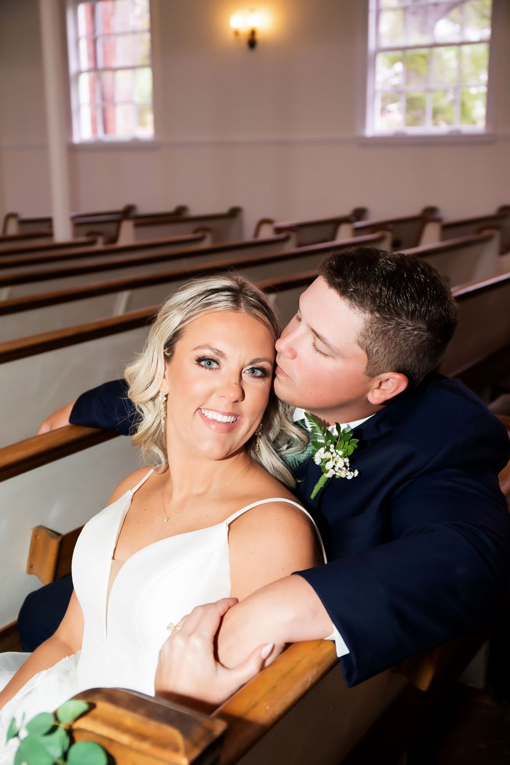 Tender moment captured between couple in wooden church pew.