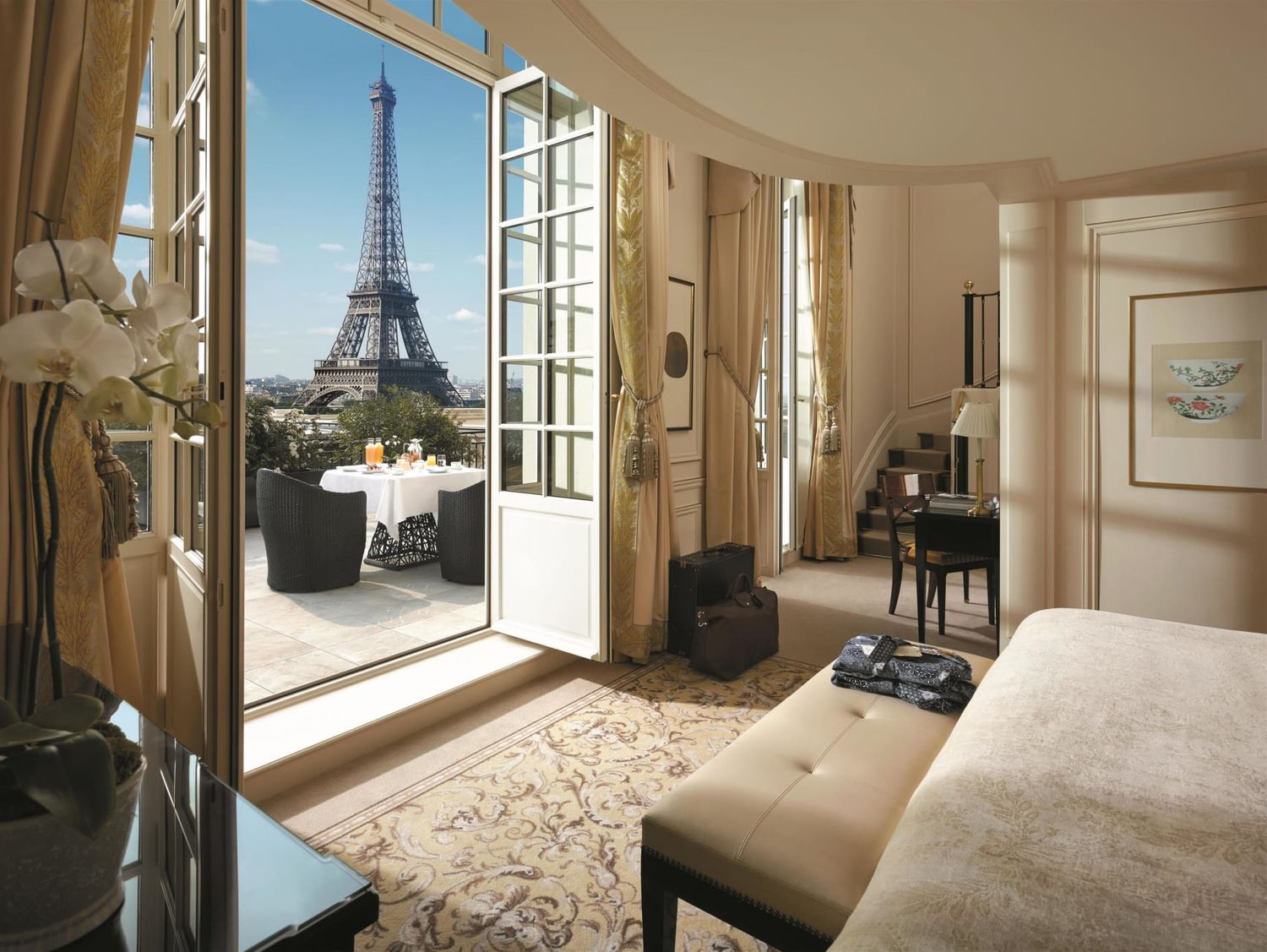 Luxurious hotel suite with French doors opening to a balcony showcasing the iconic Eiffel Tower.