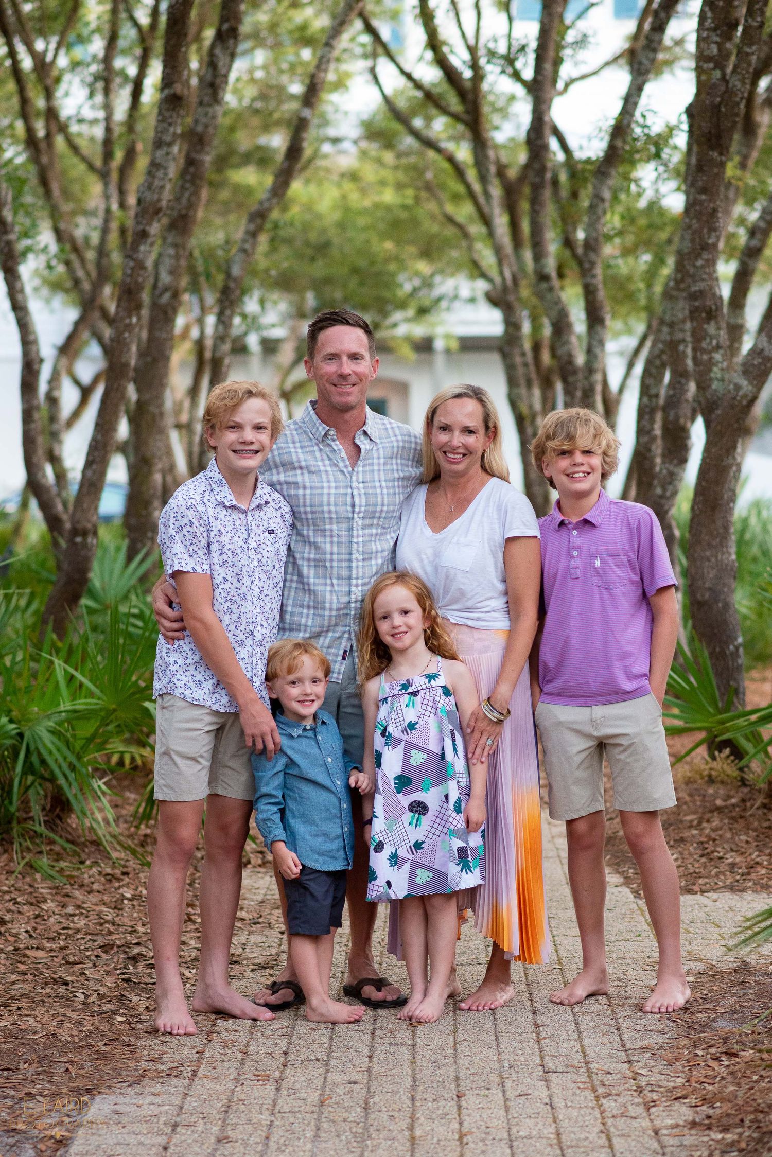 Family portrait on brick pathway surrounded by tropical vegetation.